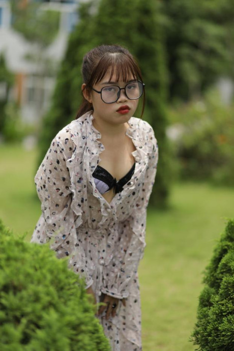 Sweet slut girl broad exposes her brassiere while kneeling between a couple of shrubs - #279505
