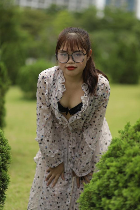 Sweet slut girl broad exposes her brassiere while kneeling between a couple of shrubs - #279506