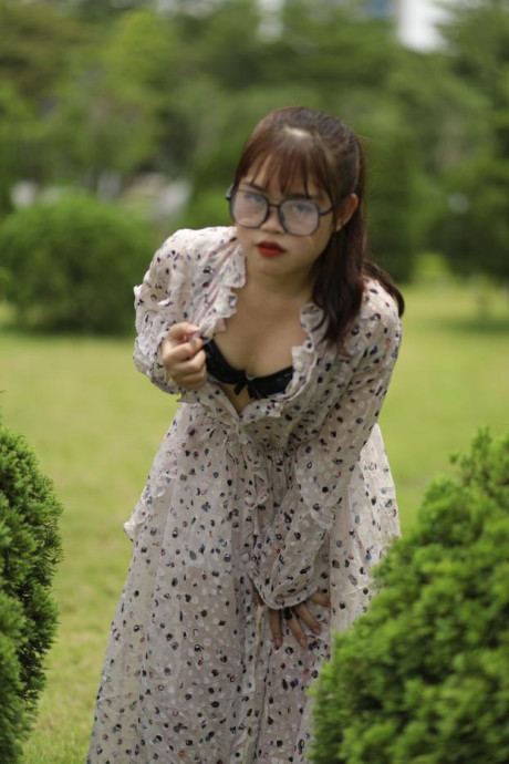 Sweet slut girl broad exposes her brassiere while kneeling between a couple of shrubs - #279508