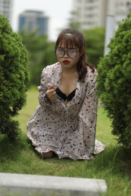 Sweet slut girl broad exposes her brassiere while kneeling between a couple of shrubs - #279511