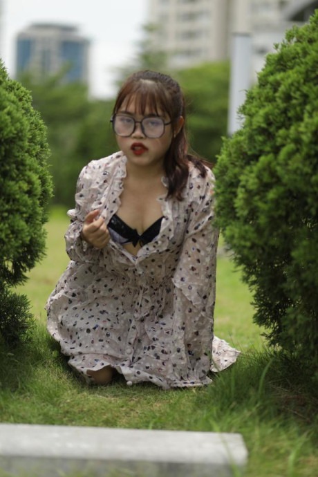 Sweet slut girl broad exposes her brassiere while kneeling between a couple of shrubs - #279513