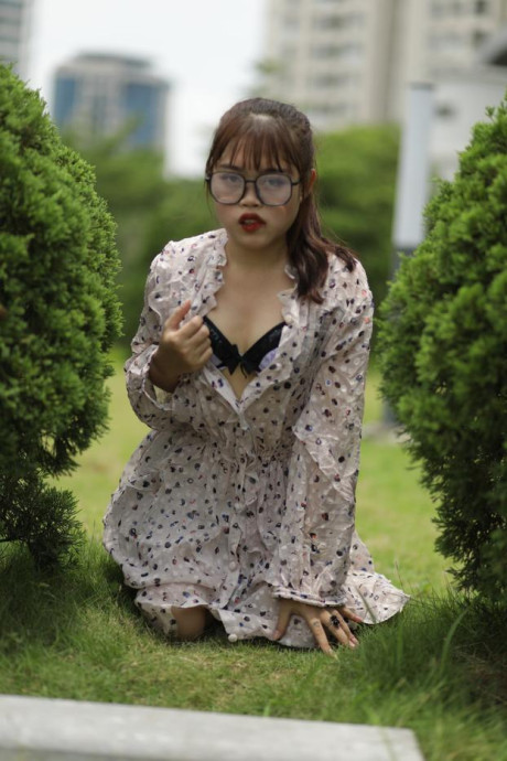 Sweet slut girl broad exposes her brassiere while kneeling between a couple of shrubs - #279516